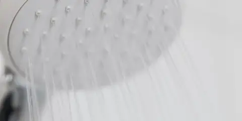 Chuveiro elétrico branco com água caindo