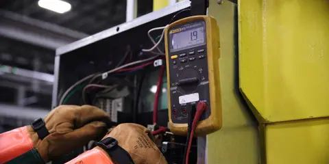 Eletricista medindo o quadro com um multímetro