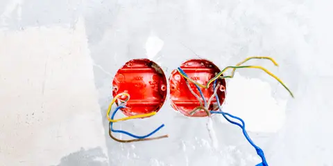Ponto de tomada aberto na parede, com os fios à mostra